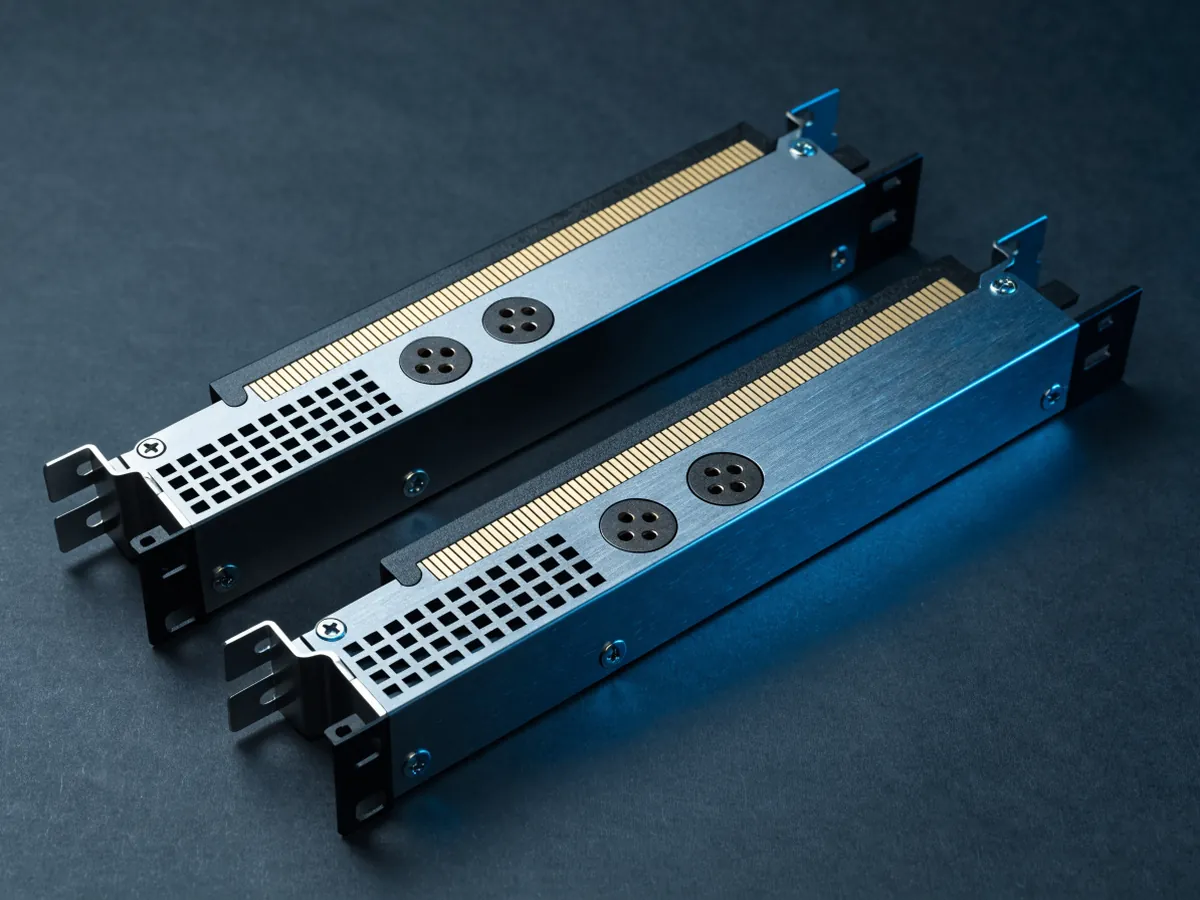 Two passive accelerator cards laid flat and overlapping, photographed from above so a wide gold bridge connector and two eight pin power sockets on the top edge are visible