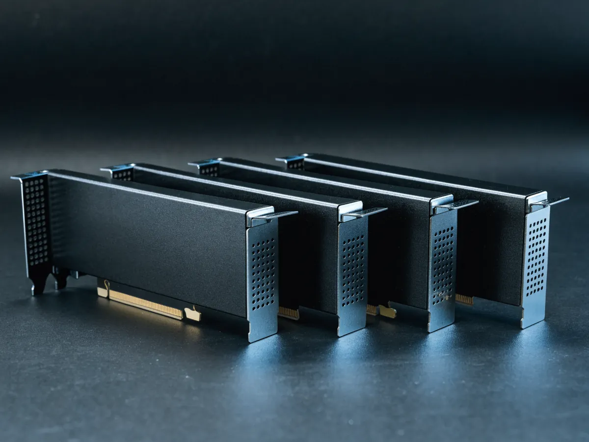 Four short single slot low profile accelerator cards laid flat in an overlapping fan, half height brackets and no power sockets, under blue studio lighting