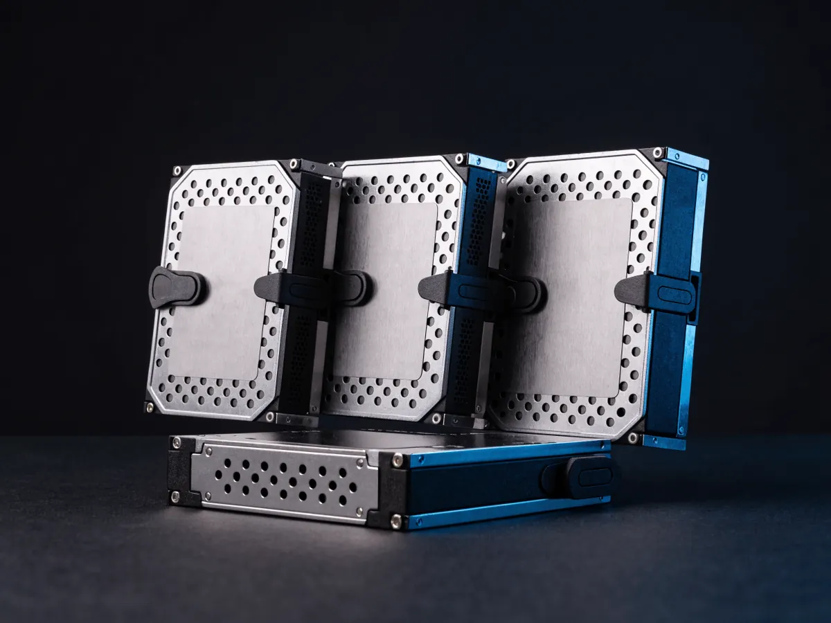Four hard drives fitted into blank metal drive carriers with plastic latch handles, three standing on edge and one lying flat
