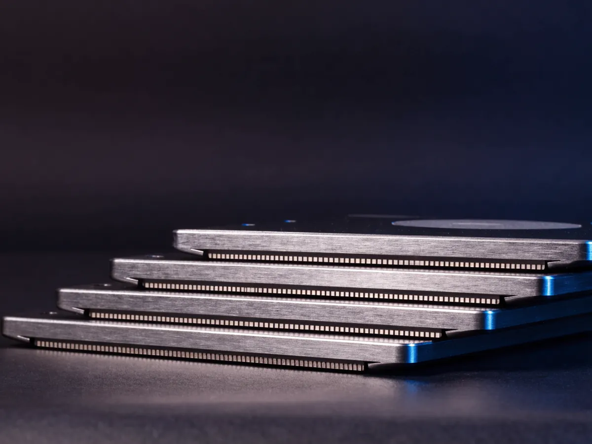 Three 3.5 inch hard disk drives lying overlapped like roof tiles on a dark surface, blank top covers facing the camera