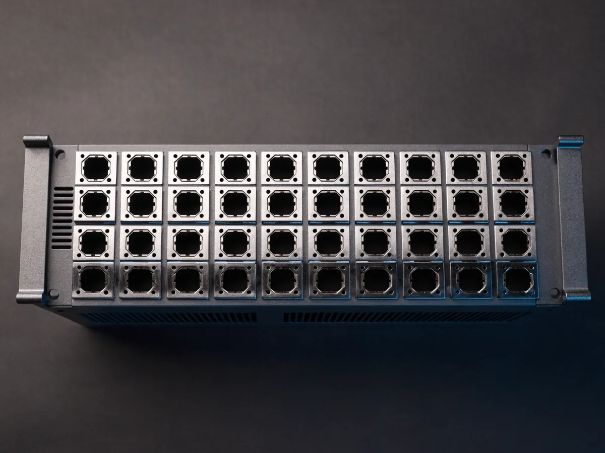 Overhead view of a 1U rackmount switch lying flat on a dark surface, showing thirty two large square empty transceiver cages along its front edge