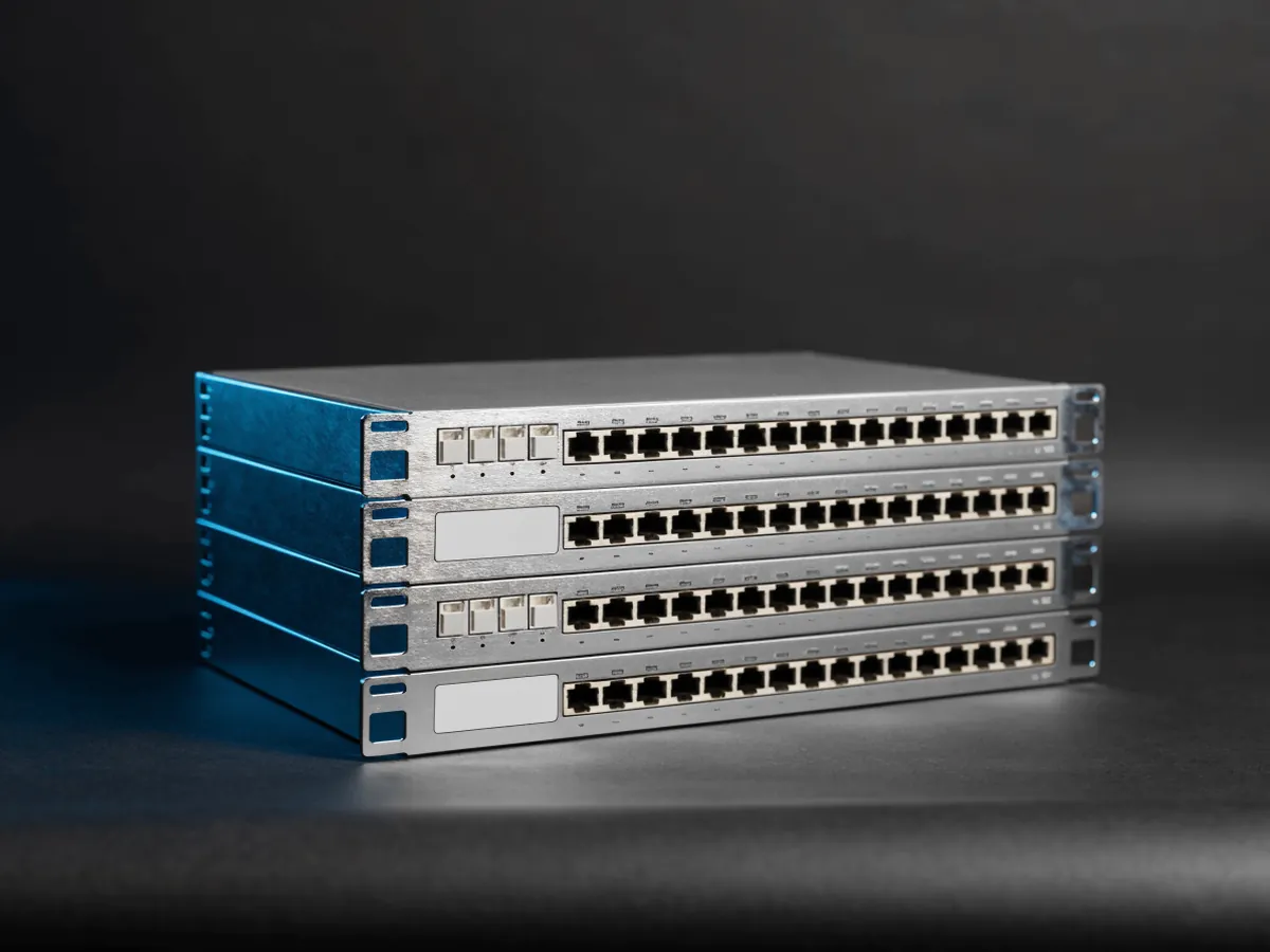 Three identical 1U rackmount switches stacked in a column on a dark background, each with a row of copper Ethernet ports and four small uplink cages