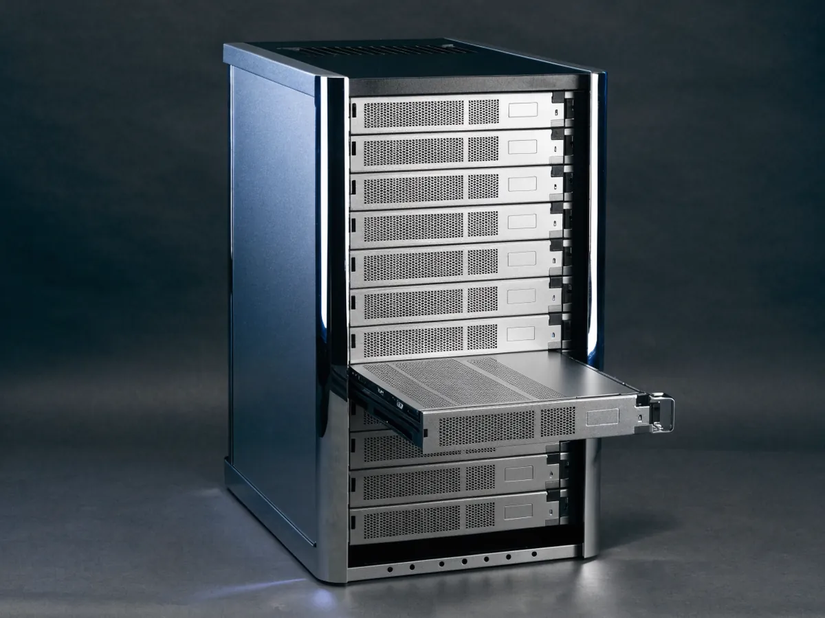 Blade server enclosure holding a row of eight vertical half height blade sleds, one partly withdrawn on its rails, photographed under cool studio lighting on a dark background