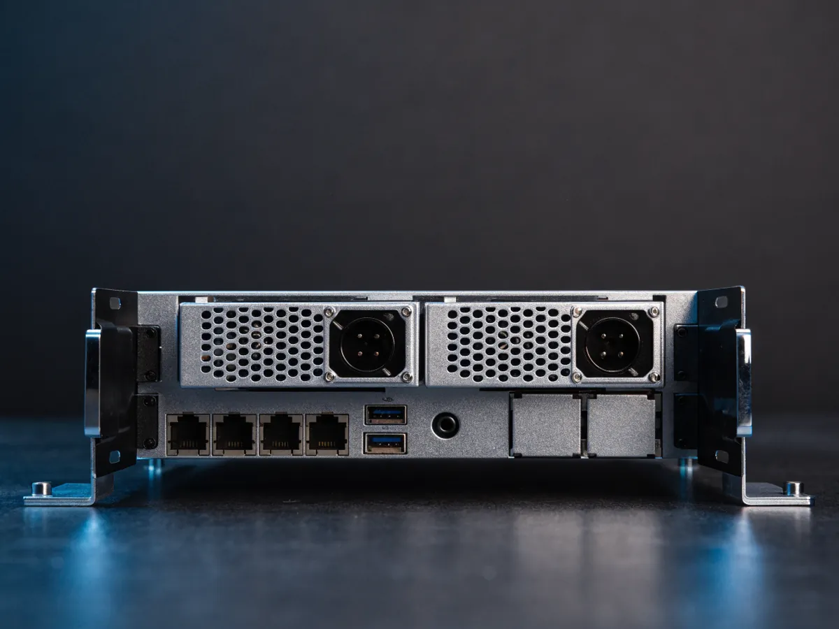 Rear panel of a 1U rackmount server showing two hot swap power supply modules, network and management ports and low profile expansion slots, lit evenly on a dark background