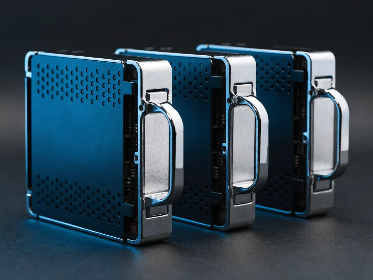 Three 2.5 inch drives seated in metal and plastic hot swap carriers with latch handles, staggered in a row with blank unmarked front faces