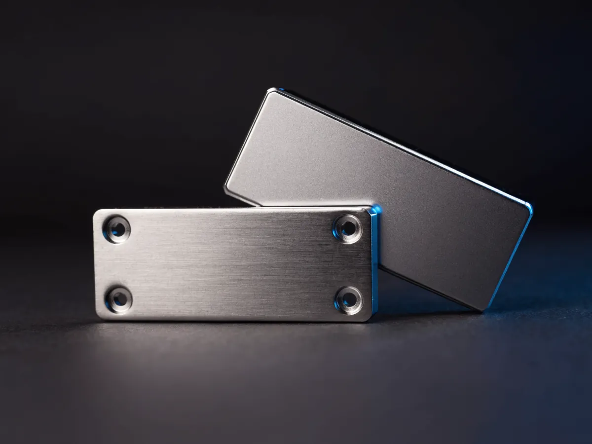 One 2.5 inch solid state drive lying face down showing its blank underside and mounting screw holes, with a second drive standing upright behind it