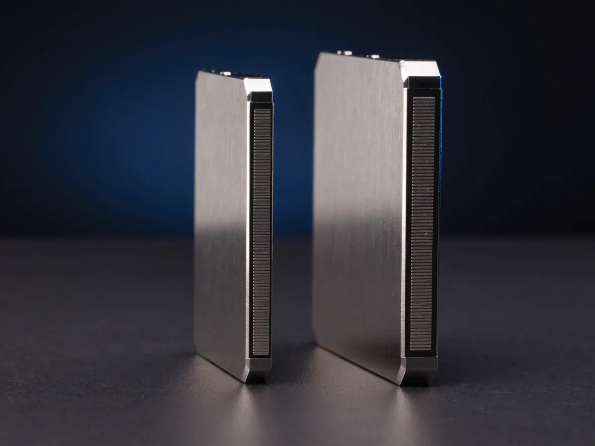 Two 2.5 inch solid state drives seen end on side by side, one thin and one noticeably thicker, showing their contact edges against a dark background