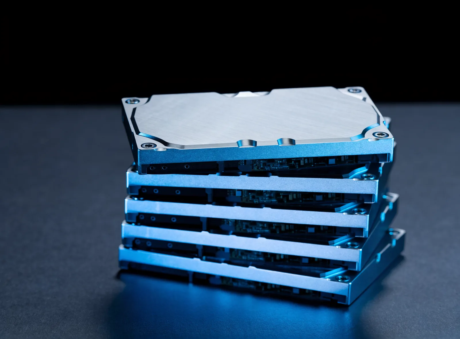 Stacked enterprise 3.5 inch SAS hard disk drives with blue rim lighting on a dark surface